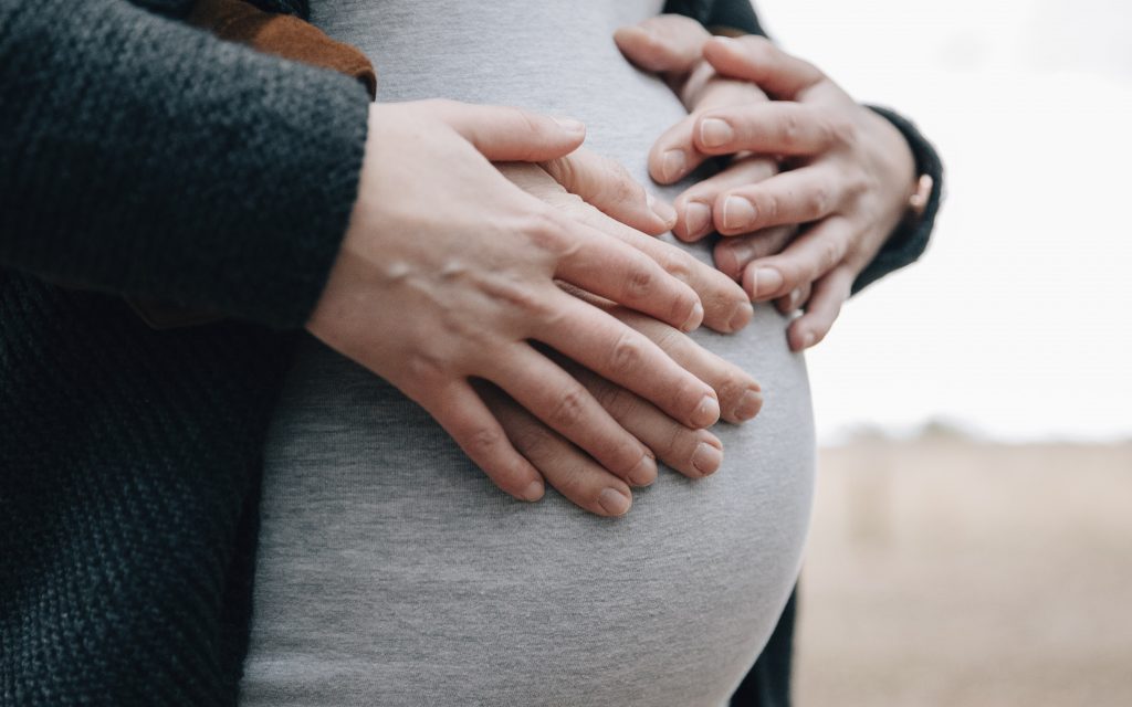 familie portret zwangerschap, vier handen op een zwangere buik