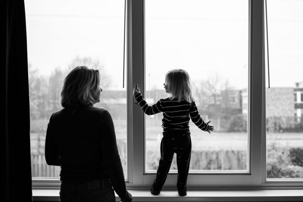 Een 'day in the life' met de familie Schoon, meisje staat op de vensterbank voor het raam en moeder staat er naast.