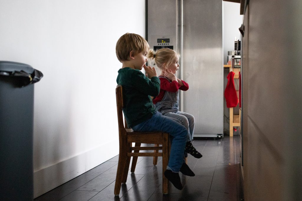 Een 'day in the life' met de familie Schoon, jongen en meisje zitten op kinderstoeltjes voor de oven.