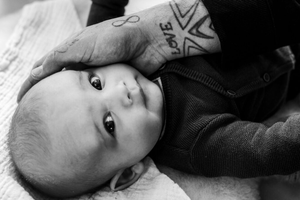 Familiefotografie Eindhoven hand vader met op zijn pols een tattoo op het hoofd van zijn zoon