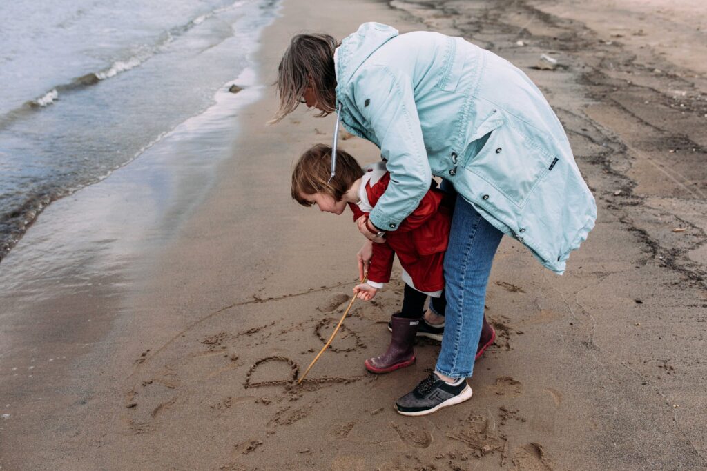 Familiefotografie Eindhoven moeder en dochter schrijven naam in het zand