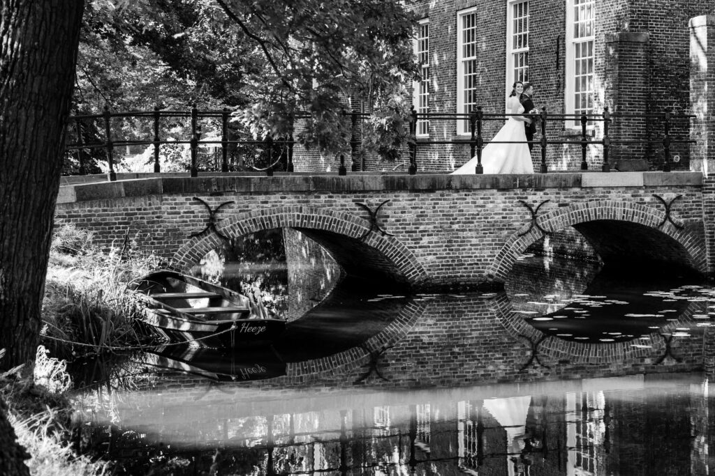 Trouwfotografie, bruidspaar loopt over een brug.